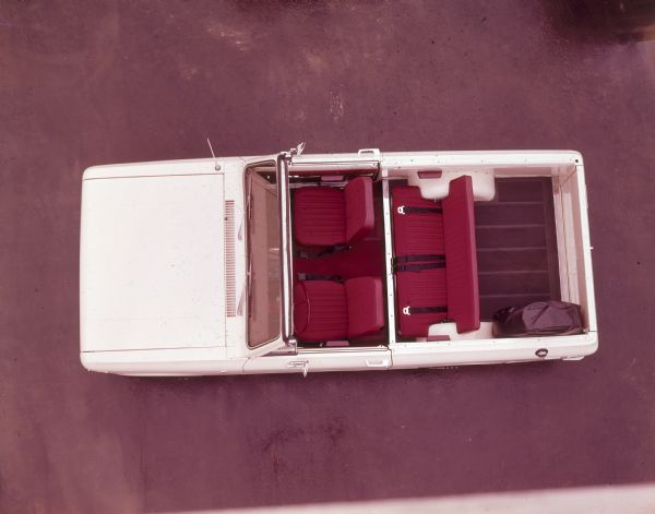 Overhead view of a white two-door Scout. Doors and windshield, no roof or sides. Small truck bed and tailgate. Red seats in front and back.
