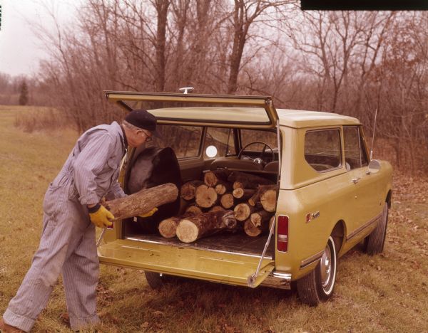 Man loading logs into back of Scout II.