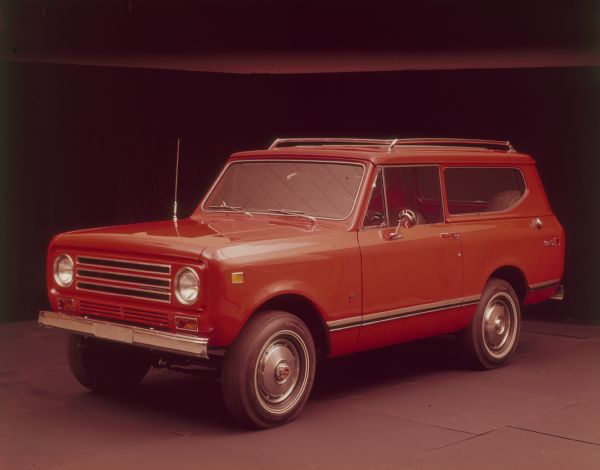 Three-quarter view from front of driver's side of red Scout II with red topper and roof rack.