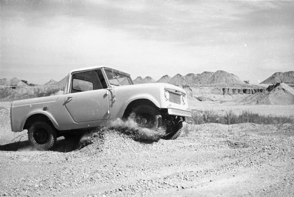 Man driving Scout pickup in a desert. The number "926" is painted on the side panel just in front of the passenger side door.