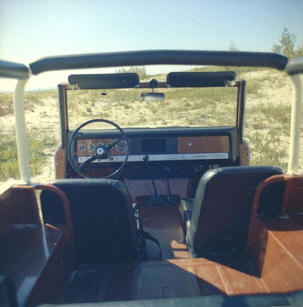 Rear view of Scout parked in dunes. Ocean in the far background.