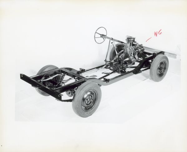 Three-quarter view from rear of passenger side of rolling chassis for a Scout 4x4. Steering wheel and drive train are exposed.