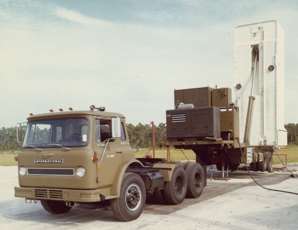 Three-quarter view from front of left side of COF-1810A Cargostar with Missile-Launch Cell in open position parked outdoors. Painted under driver's side door window is: "US ARMY."