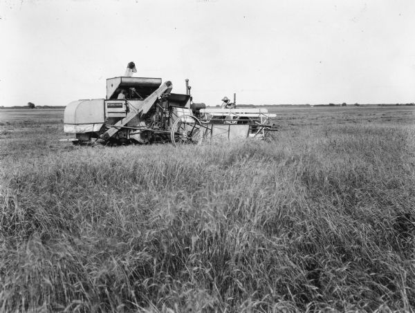 Original caption reads: "This shows the Type N experimental harvester-thresher at work near Hutchinson, Kansas, during the harvest season of 1930. The Type N machine was an enlarged version of the No. 20 harvester-thresher with 10-foot cutting platform, four-selection straw rack, and auxiliary engine. The basic design (similar to that of the No. 20) proved so satisfactory that it was later adopted for the nos. 31 and 41 harvester-threshers."