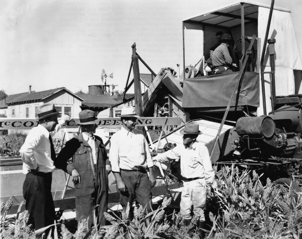 Original caption reads: "New 31-RW West Coast special harvester-thresher owned by Frank Rakow of Rio Vista, California, and shown in operation in 'gyp' (Egyptian) corn on 200-acre island farm leased by W.T. Jarrett from Liberty Farms Company. Shown, left to right, H.C. Sage, assistant branch manager, general line branch, San Francisco; G.C. Gordon of Gordon of Gordon, Hansen Company, McCormick-Deering dealers, Rio Vista; and Messrs Jarrett and Rakow"
