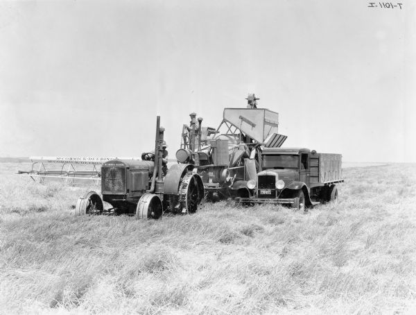 Original caption reads: "New McCormick-Deering 15-30 and new No. 40 McCormick-Deering harvester thresher, also a new A-4 motor truck with homemade grain box. This grain box holds 180 bushels of wheat. These machines are operating on the Foster Farms, Rexford, Kansas. Foster Farms own 20,000 acres of land, part of this acreage being in wheat, corn, barley, and rye. The manager of the Foster Farms at Rexford, Kansas is Mr. E.D. Mustoe."