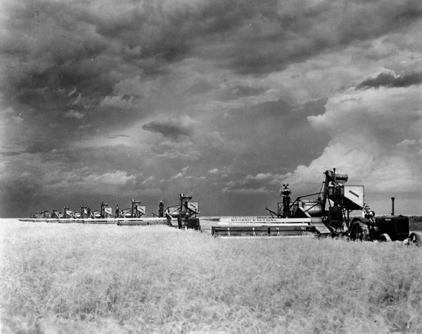 Handwritten caption on back of photograph reads: "Twelve No. 11 McCormick-Deering Harvester threshers (1927) cutting wheat on Louis Bertrand's farm outside Oakley, Kansas".