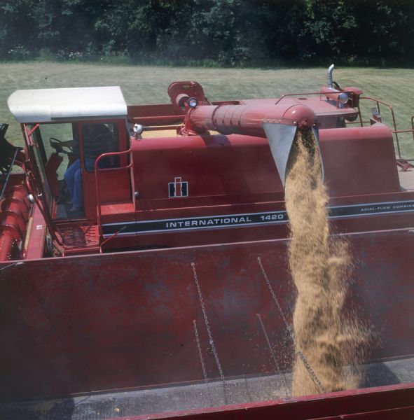 Elevated view of a man operating a 1420 Axial Flow combine and emptying the grain tank.