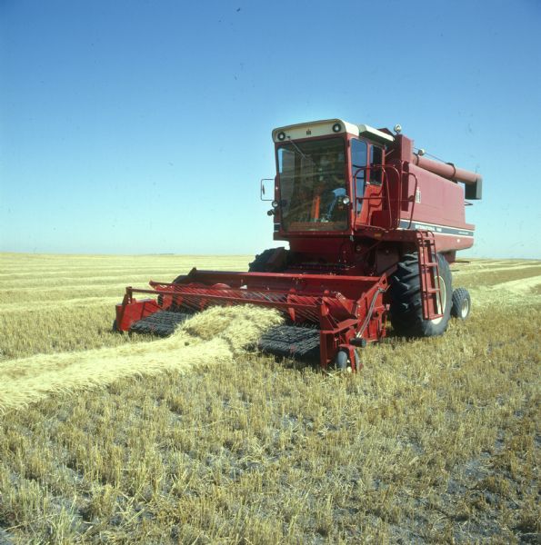 Three-quarter view from front left of a man operating a 1480 axial-flow combine in a field.