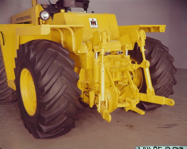 Three-quarter rear view from left side of an International Harvester 4100 tractor parked indoors. It has been painted yellow.