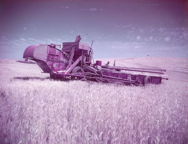 View from rear of a man using a McCormick combine in a field.