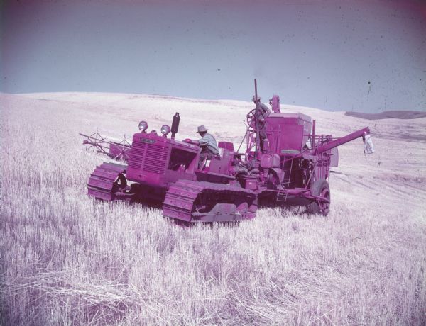 Three-quarter view from front left of a man driving an International Diesel crawler-tractor and pulling a man on a McCormick combine.