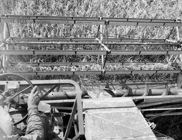Overhead view of a man operating a combine in a field. "Hume Reel" is printed on the reel.