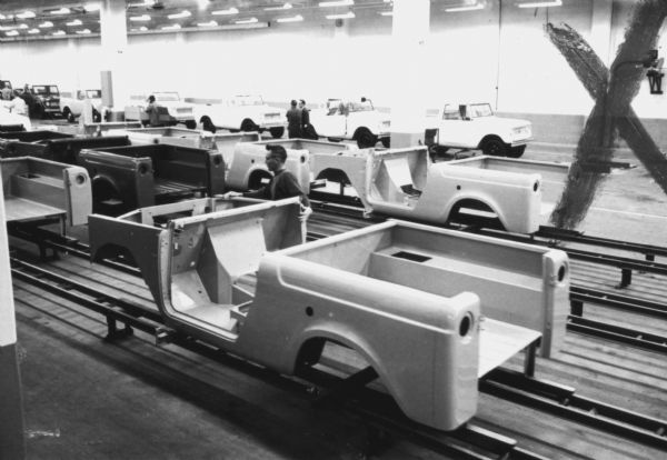 Man working with Scout bodies on an assembly line at International Harvester's Fort Wayne plant, subject of a 1961 article in <i>International Harvester Today</i> entitled "The Scout." Additional Scouts with chassis and bodies united are in the background.