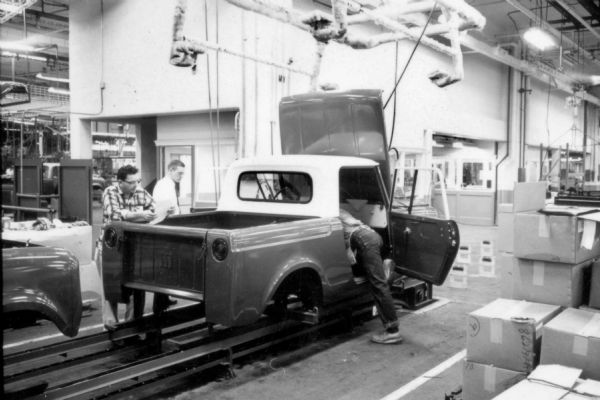 Several Fort Wayne employees are documenting and inspecting an International Scout body. The hood is raised, and one man is bending over the front seat through the open passenger side door. Assembly line image from International Harvester's Fort Wayne plant, subject of a 1961 article in <i>International Harvester Today</i> entitled: "The Scout."