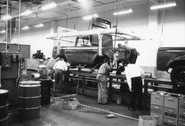 Fort Wayne employees attach the body of an International Scout to its chassis. The body is being lowered from an overhead lift. Assembly line image from International Harvester's Fort Wayne plant, subject of a 1961 article in <i>International Harvester Today</i> entitled: "The Scout."