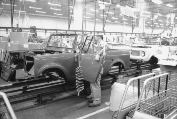 Two men working on door assembly of Scout on International Scout production line. Assembly line image from International Harvester's Fort Wayne plant, subject of a 1961 article in <i>International Harvester Today</i> entitled: "The Scout."
