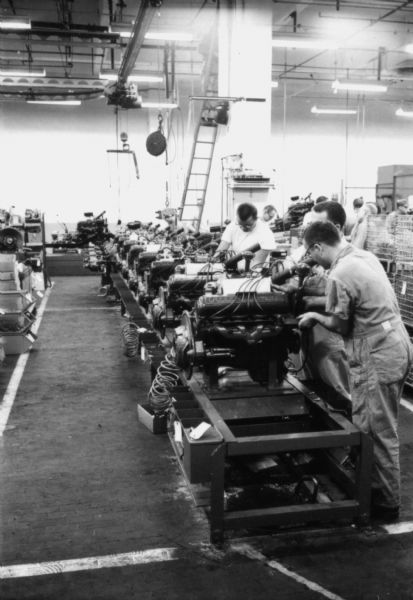 Men working on International Scout engines. The engines are being tuned and adjusted prior to assembly within the International Scout, Fort Wayne, Indiana. Assembly line image from International Harvester's Fort Wayne plant, subject of a 1961 article in <i>International Harvester Today</i> entitled: "The Scout."