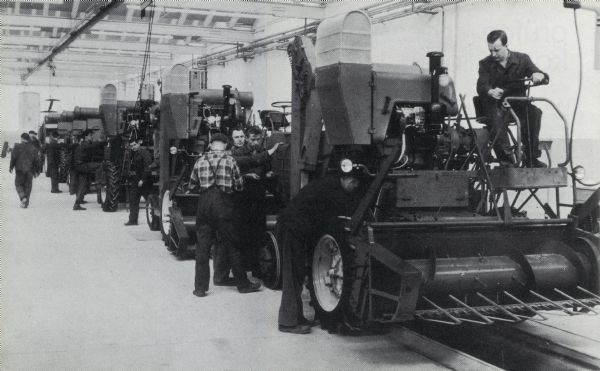 Men in factory on production line with combines in Germany.