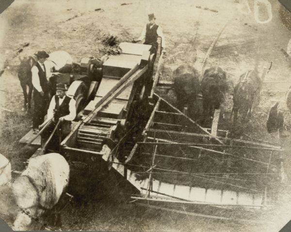 Elevated view of three men using a horse-drawn combine. Letter accompanying the image reads: ". . . we are mailing you to-day, picture of the first Combine made and operated in Oregon. This Combine was built at McMinnville, Oregon, constructed out of Binder and Separator."