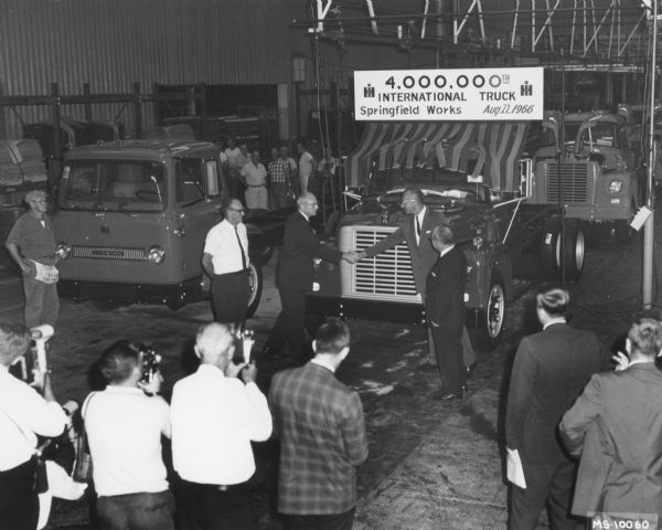 Elevated view of plant officials exchanging handshakes in front of the 4,000,000th truck built at Springfield as it rolls off the assembly line. Loadstar Model 1700.