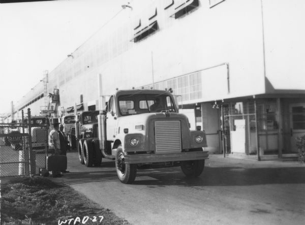 View from front of an International Truck leaving San Leandro plant. Two men are standing near the gate.