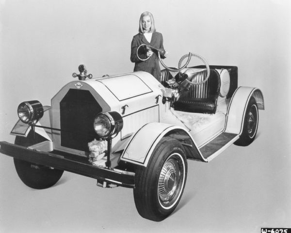 A woman poses with a Stutz Bearcat built on a Scout 4x2. She is holding a car horn in her hands.