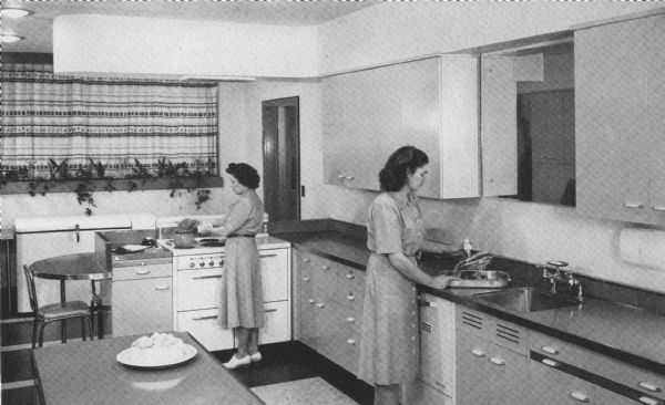 View of the new home economics department kitchen. Zelma Purchase is at the range and Priscilla Cobb is standing at the sink.