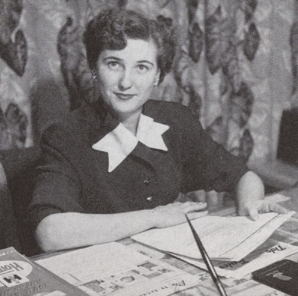 Miss Mae Houston, director of the home economics laboratory at Evansville, sitting at a desk.