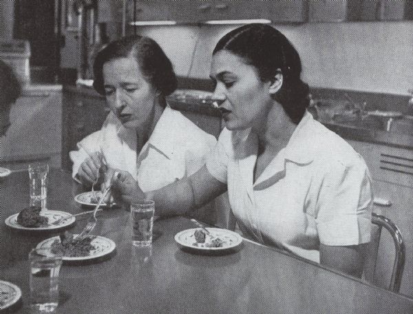Two women tasting and comparing cooked patties at International Harvester's refrigeration works.