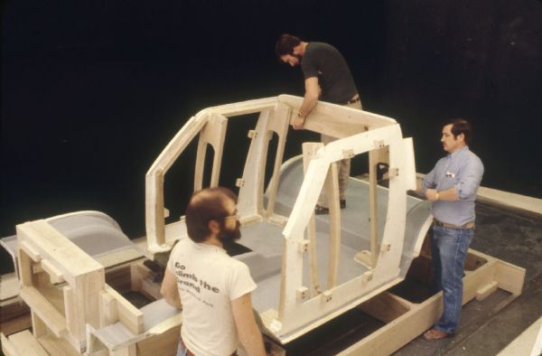 Slightly elevated view of three men working indoors on a Scout model.