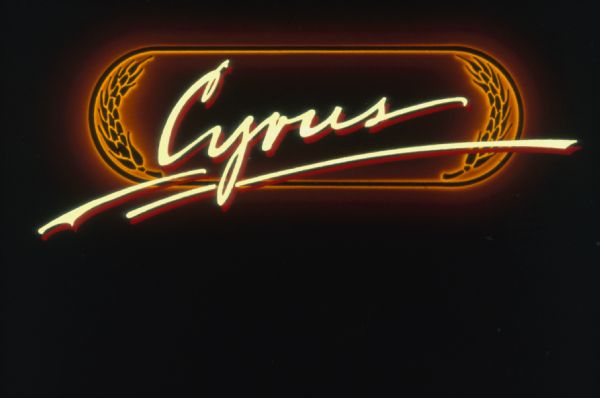 Logo for "Cyrus: The Musical" a play commissioned by International Harvester in the early 1980's. The word "Cyrus" is written in italics over an orange oblong-framed background with stylized stalks of wheat.