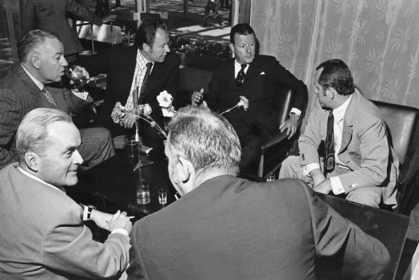 Brooks McCormick sitting and talking with a group of men around a small coffee table. The location may be in Poland.