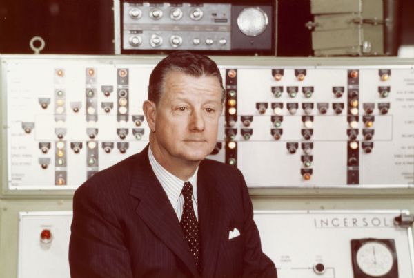 Quarter-length portrait of Brooks McCormick. Behind him is an instrument panel, with the name "Ingersol" on it.