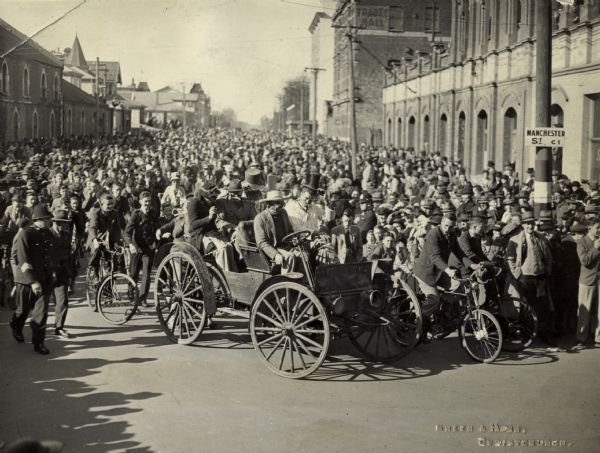 Original caption reads: "This photograph appeared in the Christchurch 'Press' dated 18th August, 1945. The procession for Peace Day Celebrations was held on the 17th August, 1945. A Motor Car of 1908 [or 1906.] A feature of yesterday's Victor Procession in Christchurch was a 1908 two-cylinder International Motor car which traversed the streets of Christchurch under its own power. This old-fashioned, solid tyred car is the property of its first owner, Mr. W. Cook, Lyndhurst, Mid-Canterbury, who brought it 54 miles to Christchurch so that it could participate in yesterday's celebrations. Mr. Cook was one of the pioneer drivers of motor-cars in Canterbury, and the old International is the second car he has owned and driven."