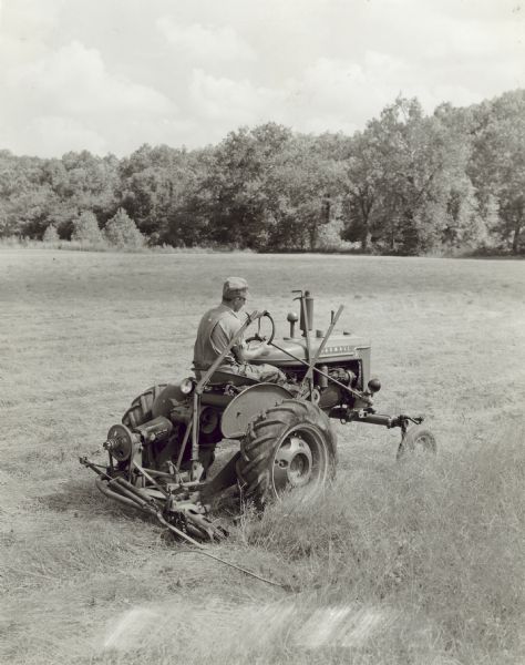 Man using Farmall A and mower, owned by J.W. Mead.