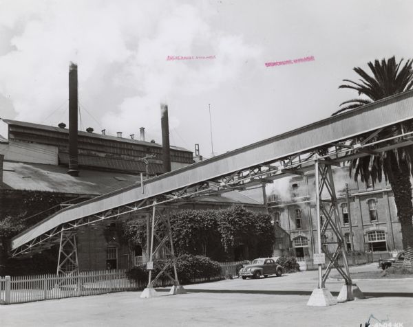 View across street towards factory buildings at a sugar refinery.