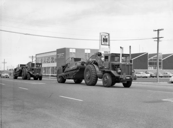 View from side of street towards two 495 Payscrapers driving in New Zealand. In the background is an International Harvester Company of New Zealand building.  