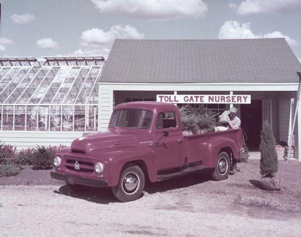 R-120 truck with pickup body parked outdoors. A man is loading or unloading the truck in front of the open door. Above the door is a sign that reads: "Toll Gate Nursery."