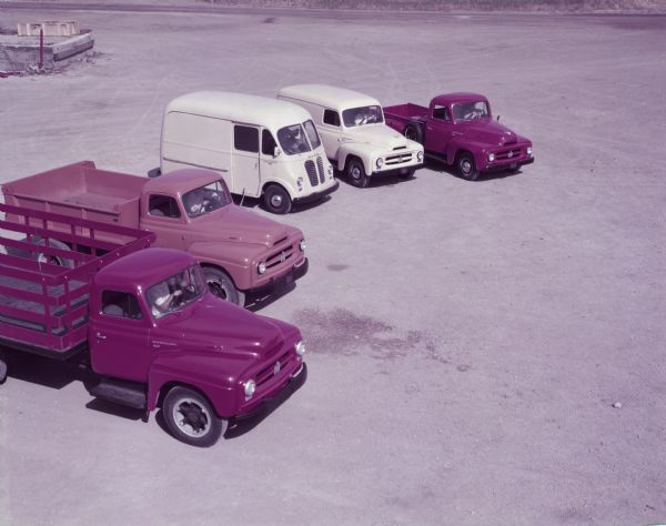 Elevated view of five R-Line trucks parked in a row outdoors. Five men are sitting in the driver's seats of each truck.