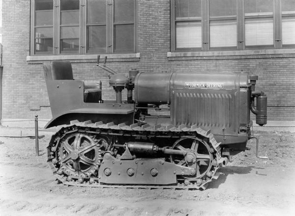 Right side view of a redesigned McCormick-Deering 10-20 Tractractor parked outdoors in front of a brick building.