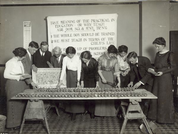 A group of male and female Cook County teachers studying corn, preparatory to taking up this work in their rural schools.