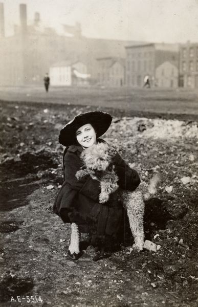 Miss Josephine Huddleston posing with dog. She had been driving the big IHC tractor at Harrison and Jefferson Streets for Chicago's City Garden Campaign.