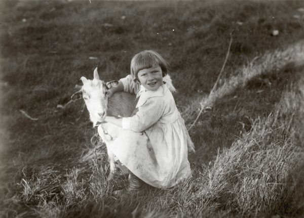 Girl with goat outdoors.