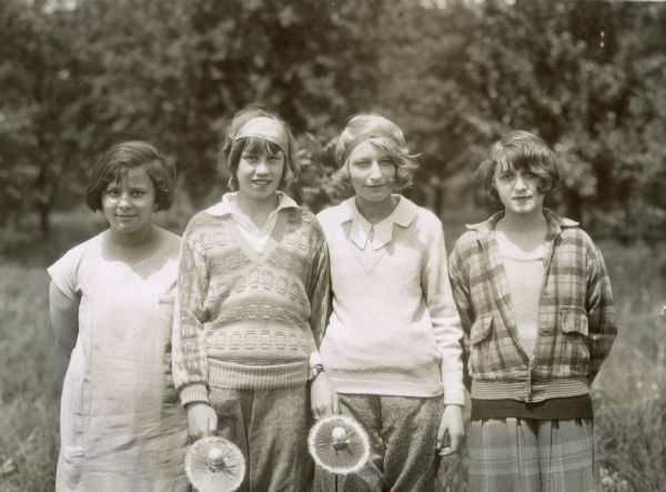 Outdoor group portrait of eighth grade girls in the Boys and Girls Club. Two of the girls are holding small dolls.
