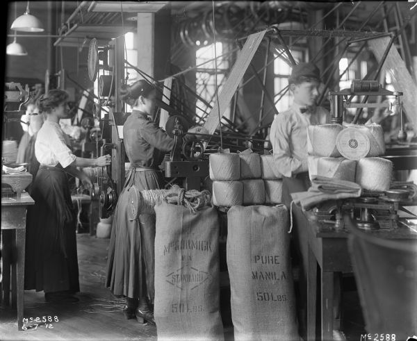 Women working in the twine mill at International Harvester's McCormick Works. In the foreground in front of the machinery are fifty pound bags of manila, and balls of twine are stacked nearby.