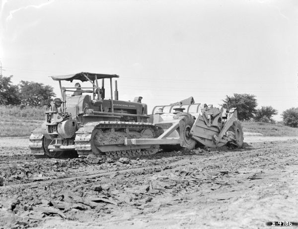 Man driving a TD-24 Crawler Tractor with a a La Plante Choate 20-yard wheel scraper.