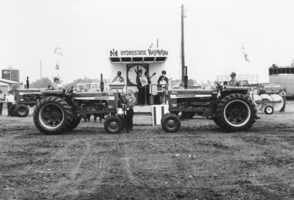 An International 544 and an International 656 flank the five piece music group at the "Hydrostatic Hullabaloo." An IH ventriloquist and dummy also appear in front of the main stage in promotion of International's Hydrostatic drive. It appears an International 656 also appears in the background of this photo.