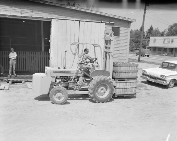 Man operating a 340 tractor with Harlo lift to move crates.