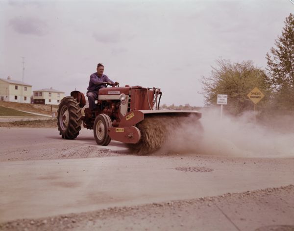 Man operating 240 Utility Tractor with Sweepster.